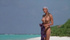 Sunbathing blonde is naked on the beach while talking to a ghost.